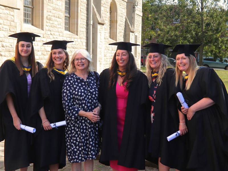 HE Graduates celebrating with their lecturer at the graduation ceremony.