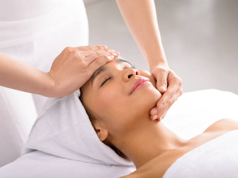 Woman receiving facial massage in spa salon