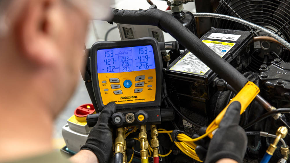Student using refrigeration and air conditioning measuring equipment in the workshop.