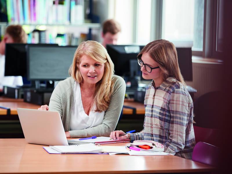 Student support staff sat helping female student 