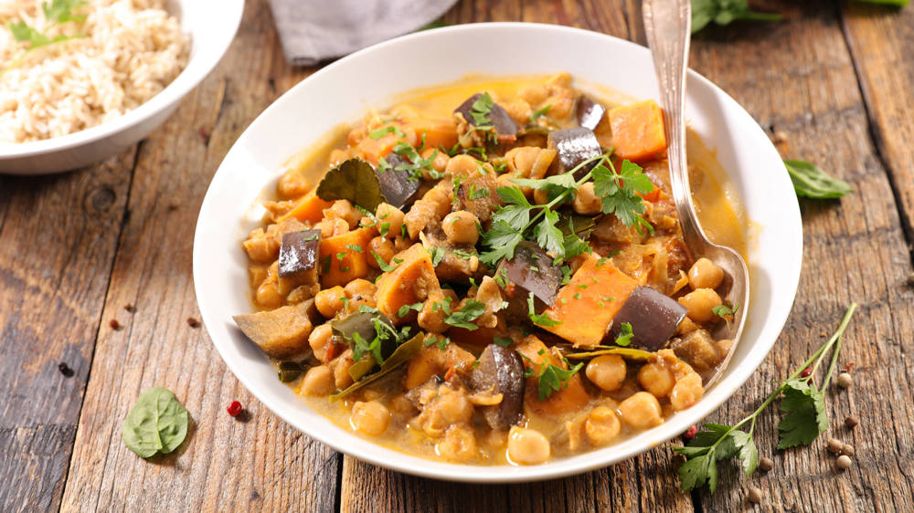 Aubergine curry and rice presented with garnish on a rustic wooden table