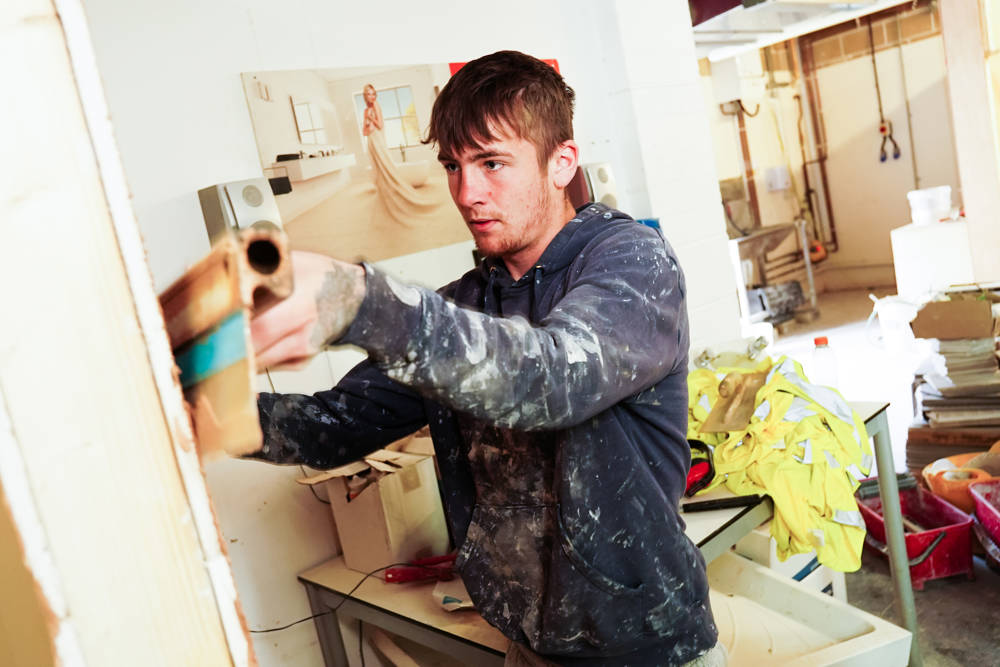 A student levelling plastering on a wall at City of Portsmouth College 