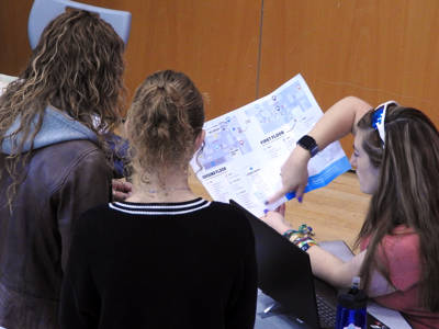 A staff member shows two women a map of the campus