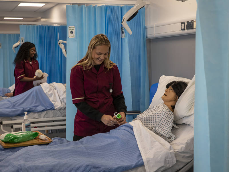 Two Health and Nursing students tend to patients  in the training ward at City of Portsmouth College 