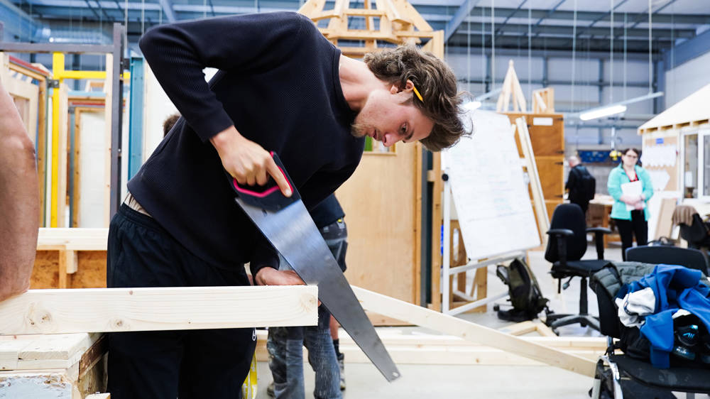 Carpentry student sawing wood in the workshop at North Harbour Campus
