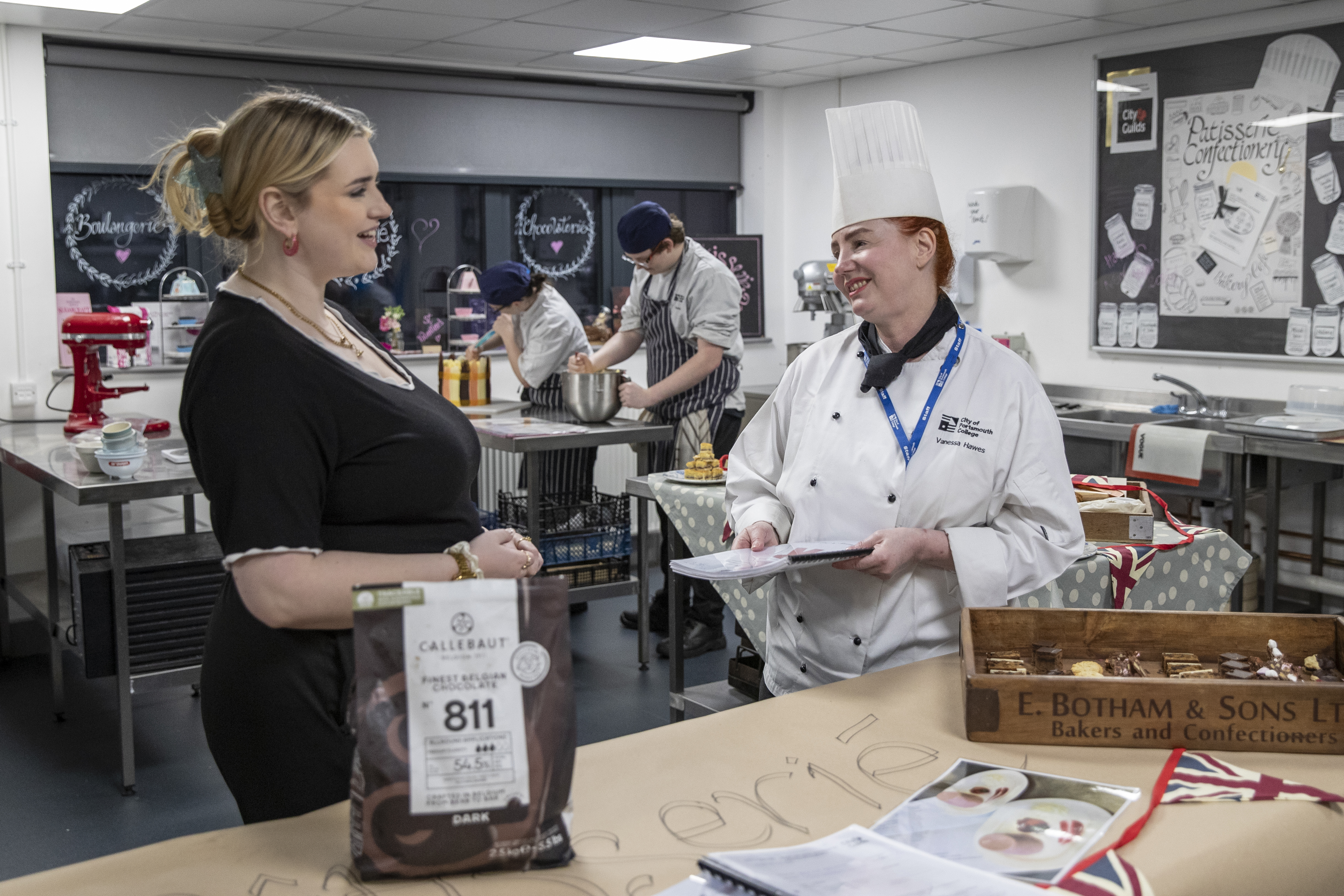 A staff members talking to a Catering lecturer at City of Portsmouth College Open Event. 
