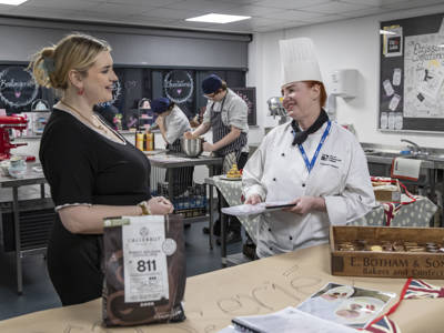 A staff members talking to a Catering lecturer at City of Portsmouth College Open Event. 