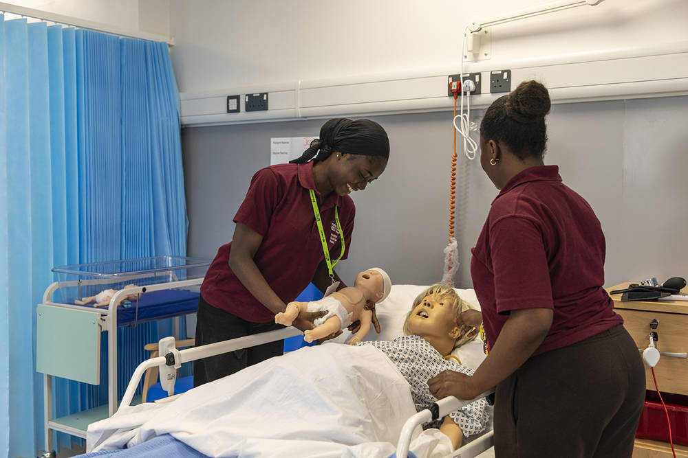 Two Health Care students in a practical simulated session at COPC's mock ward learning environment.