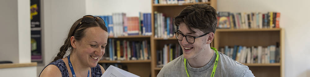 A COPC student and member of support staff in a meeting. They are both happy and smiling.