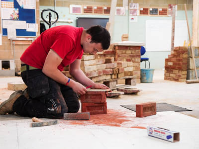A male student measuring bricks in a bricklaying workshop 