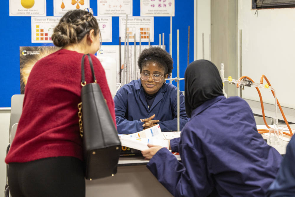 A science student sitting at an experiment desk at City of Portsmouth College