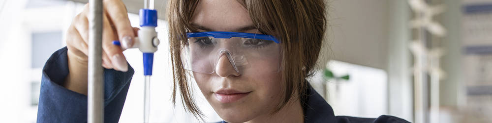 A close up image of female student with safety goggles in a practical science session.
