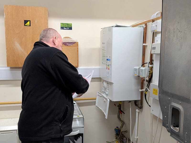 Gas engineer inspecting and testing a wall mounted boiler during ACS CCN1 gas safety training and reassessment.