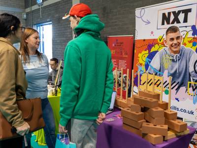 Two attendees of Moving Forward 2026 speak to an exhibitor