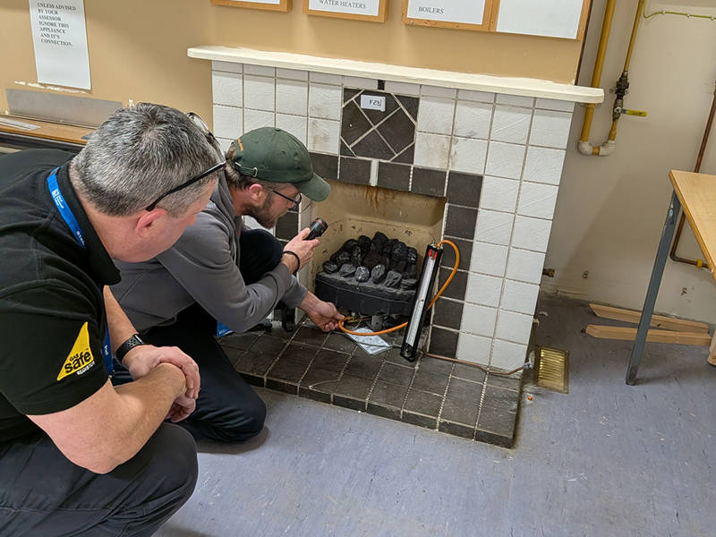 A gas trainer and trainee investigating a gas fire.