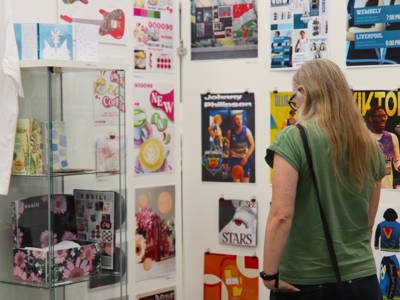 A visitor looking at a wall of artwork 