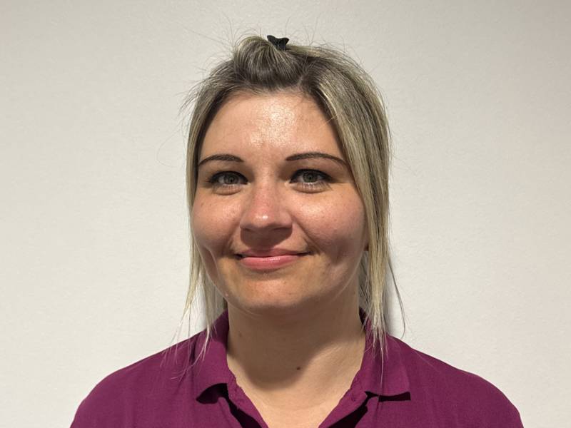 Portrait of Jo, Nursery Practitioner at Honeypot Nursery, smiling and wearing a purple uniform, with over 10 years’ experience supporting babies’ development and early learning.