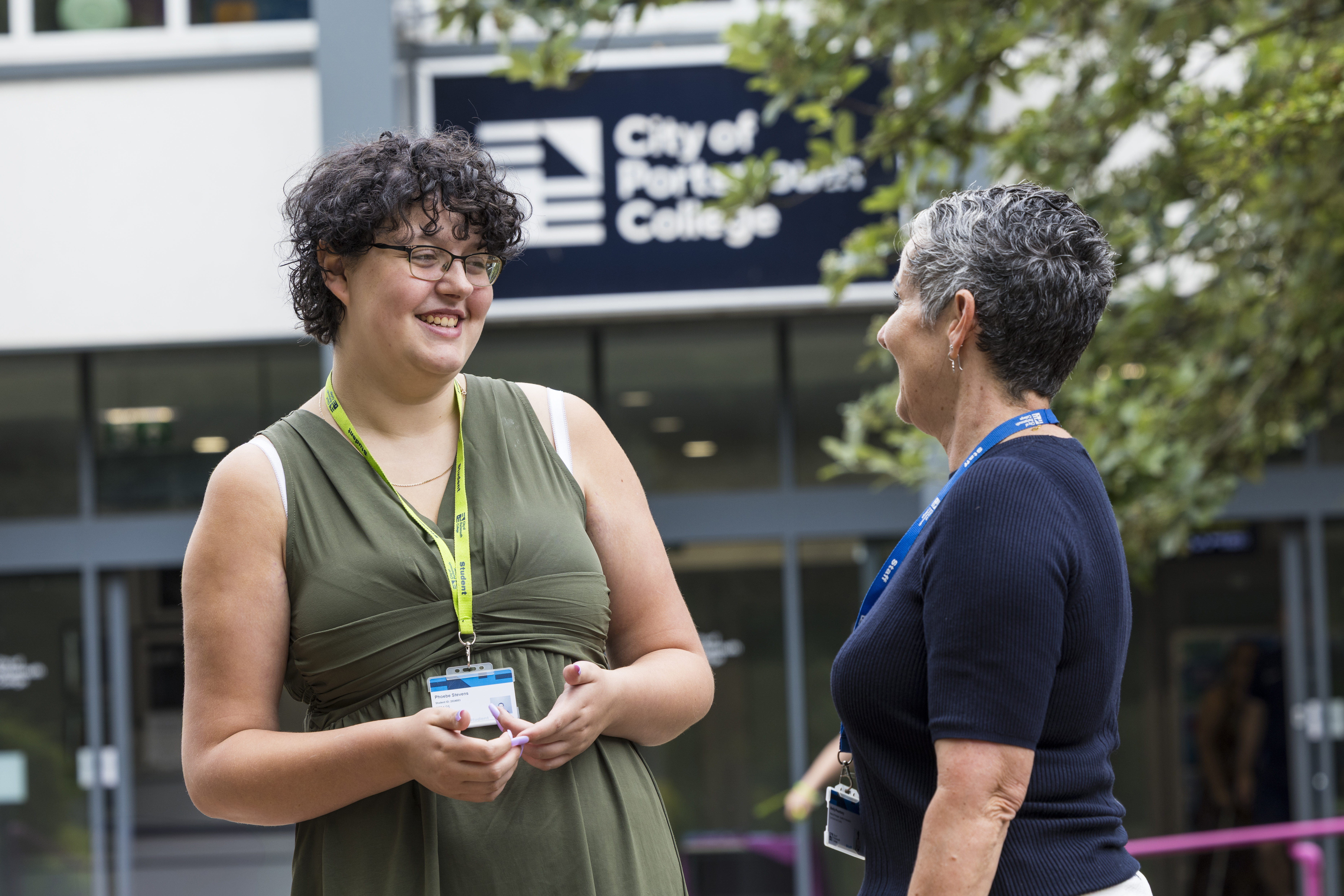 A staff member and student interacting outside City of Portsmouth College 