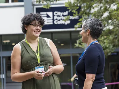 A staff member and student interacting outside City of Portsmouth College