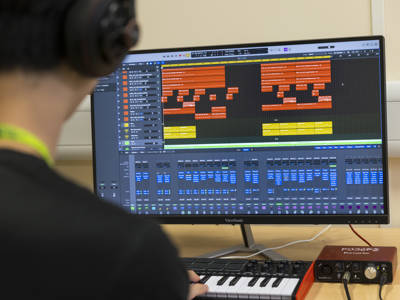 A student using music recording software on a computer 