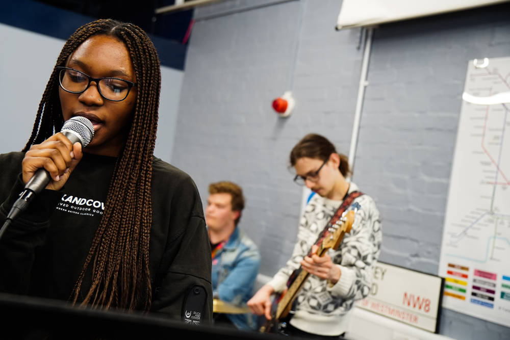 Female music technology student holding microphone in studio.