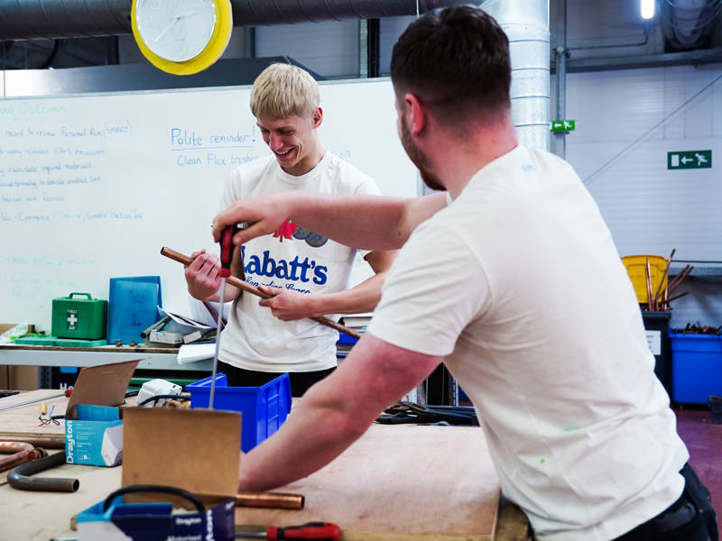 Plumbing students smiling and working in the plumbing workshop at North Harbour Campus
