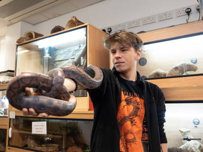 A student holding a snake in the Animal Care classroom 