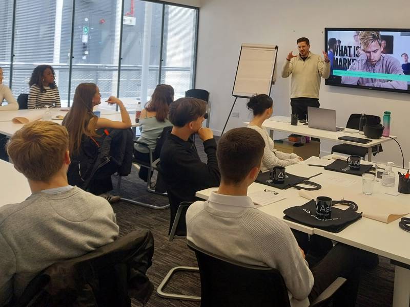 Marketing students in a classroom watching a presentation by a representative of Astute People