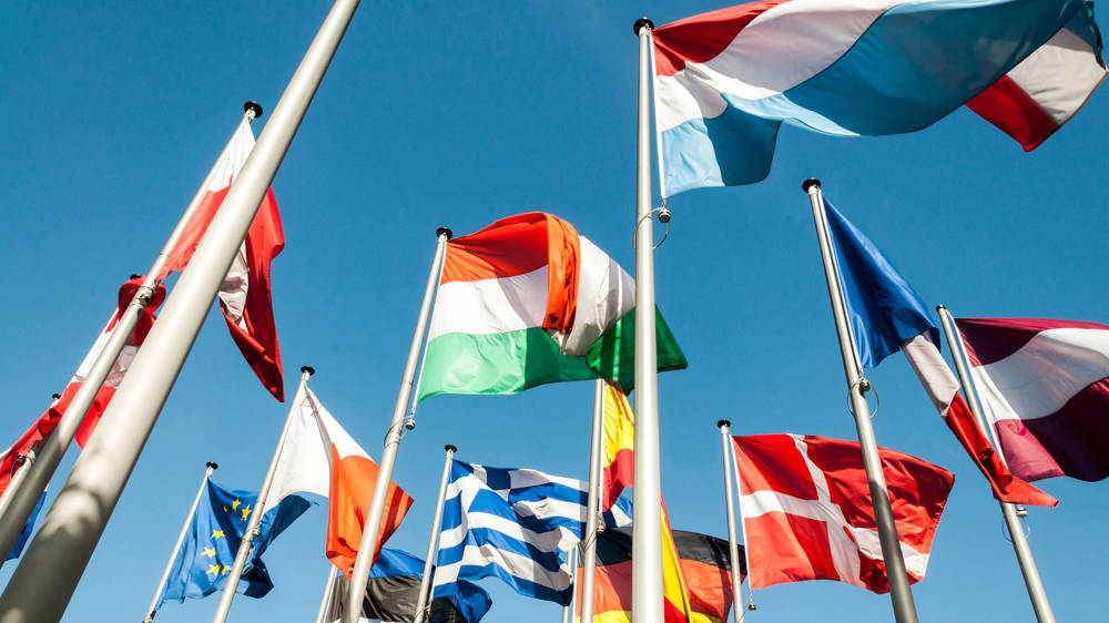 European Flags wave in the wind in front of blue sky