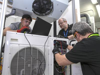 Students and a lecturer configuring an air conditioning unit 