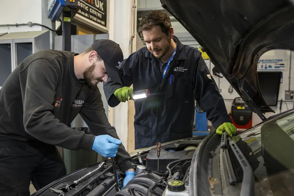 An automotive student working on a car at City of Portsmouth College