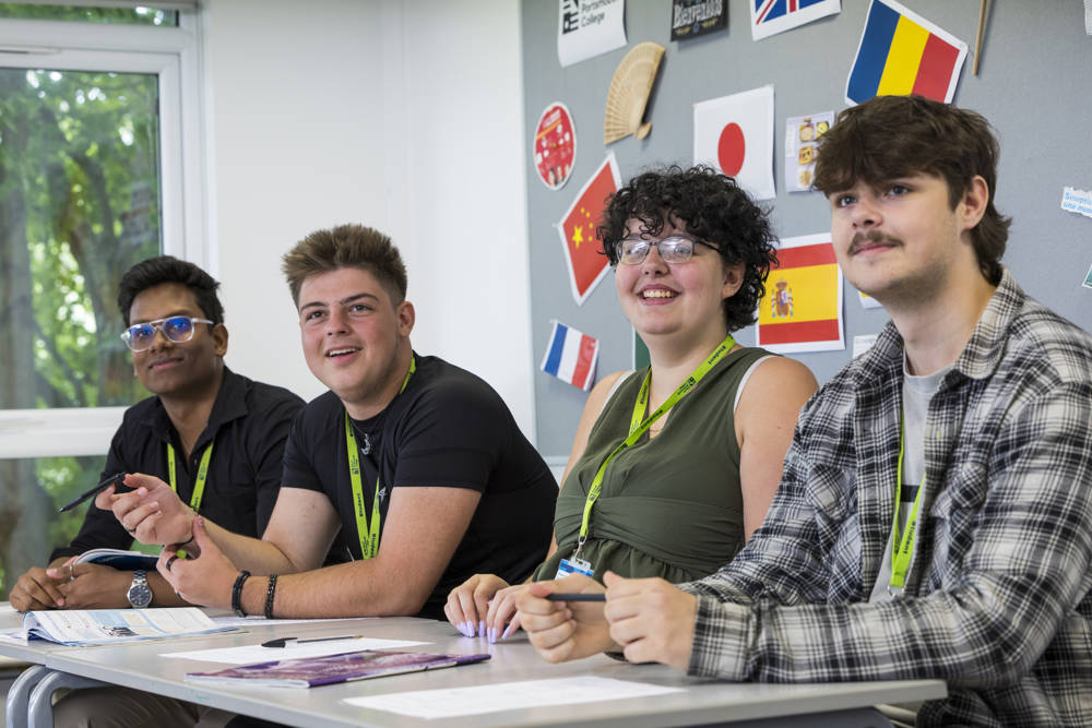 Four students sitting at a desk in a languages class