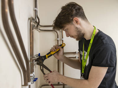 A plumbing student working with copper piping 
