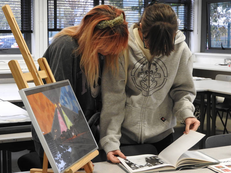 Two girls look through a picture book