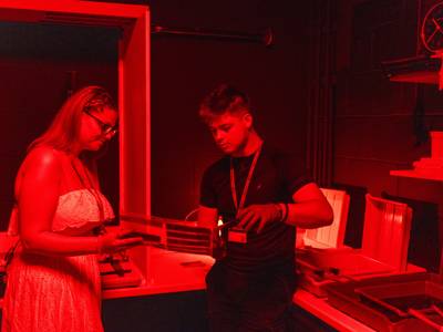 Two students looking at photograph negatives in a photography dark room 