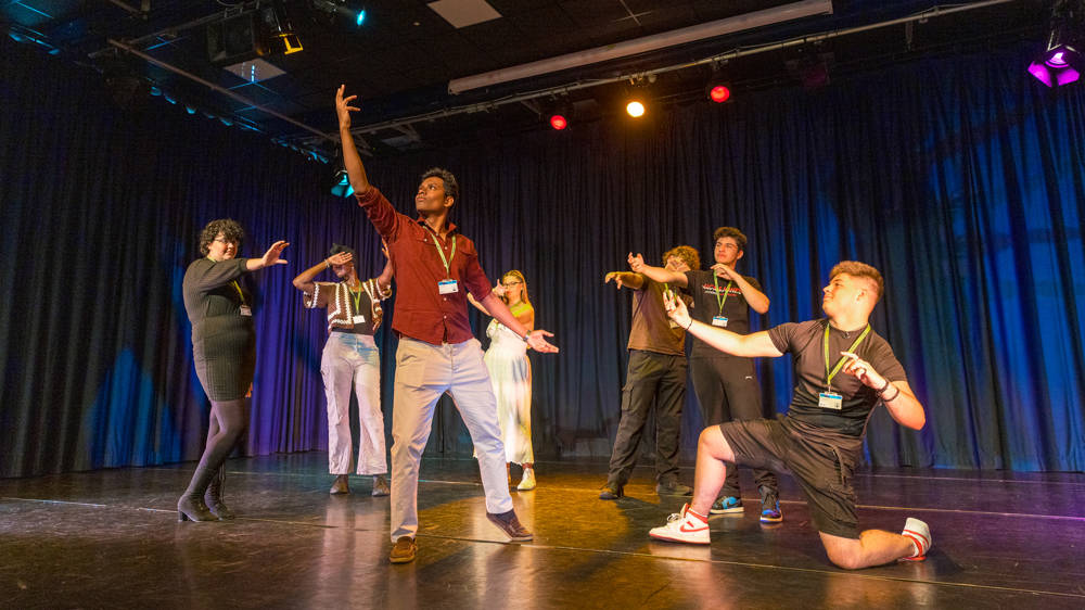 Group of performing arts students on stage during performance in the theatre.