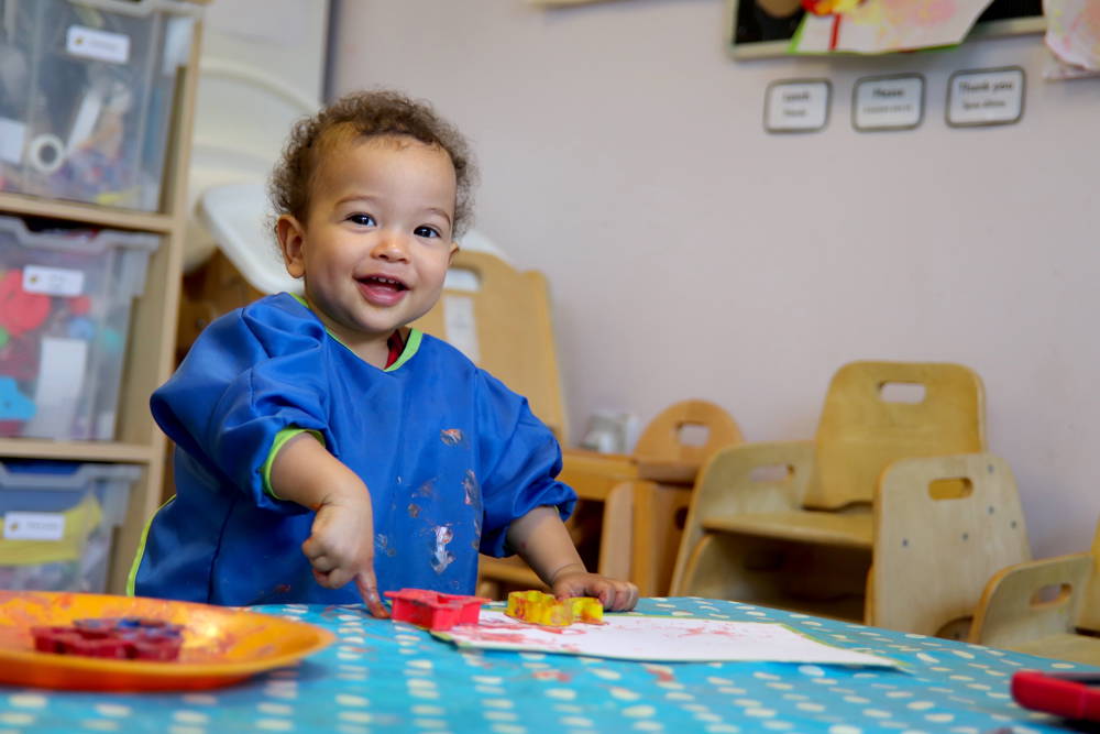 Small child, happily finger painting.