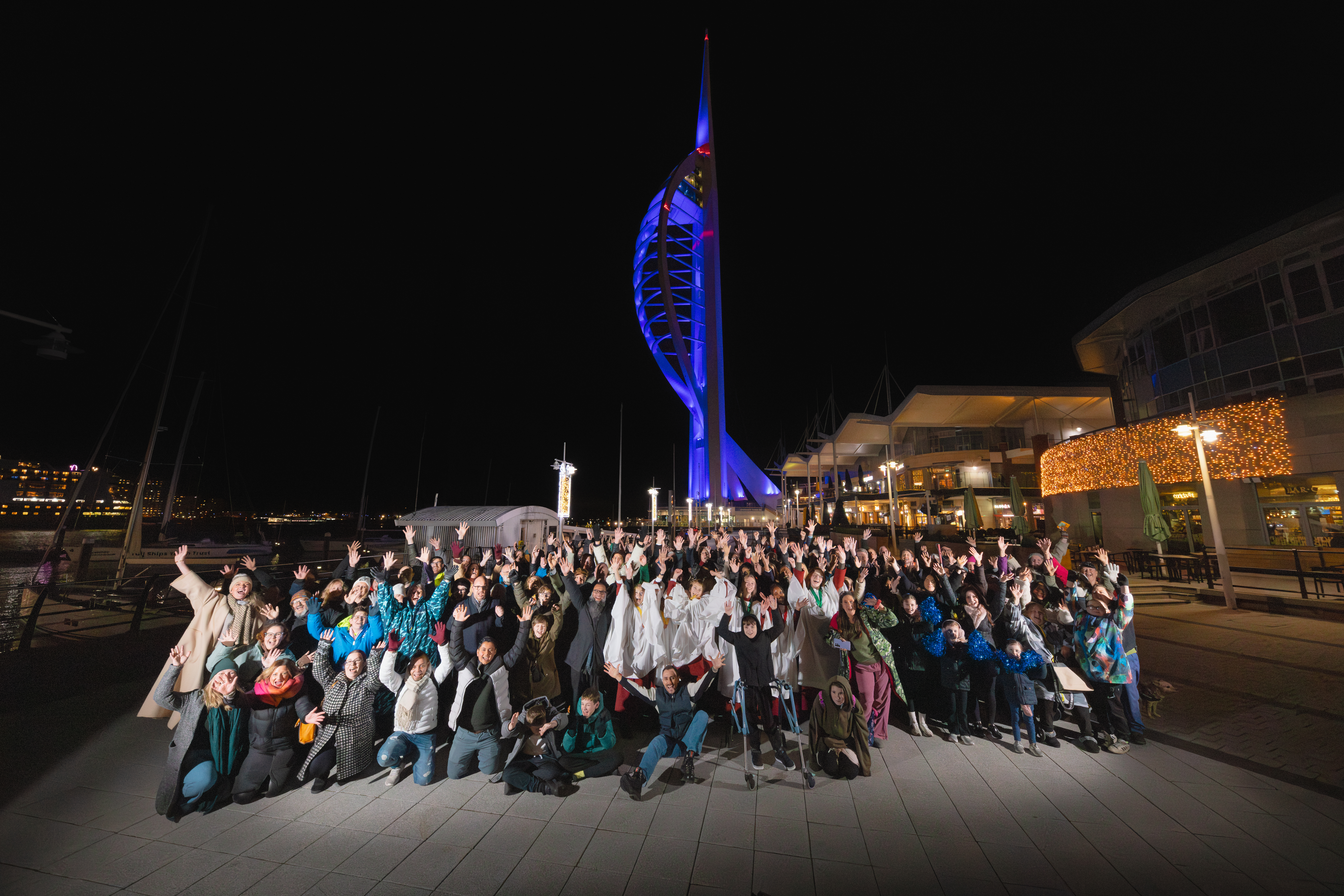 A group of people cheering in front of Portsmouth's Spinnaker Tower