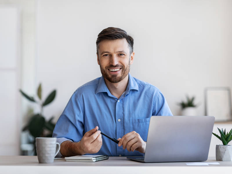 Friendly male business manager sitting at his desk in a modern office, smiling.