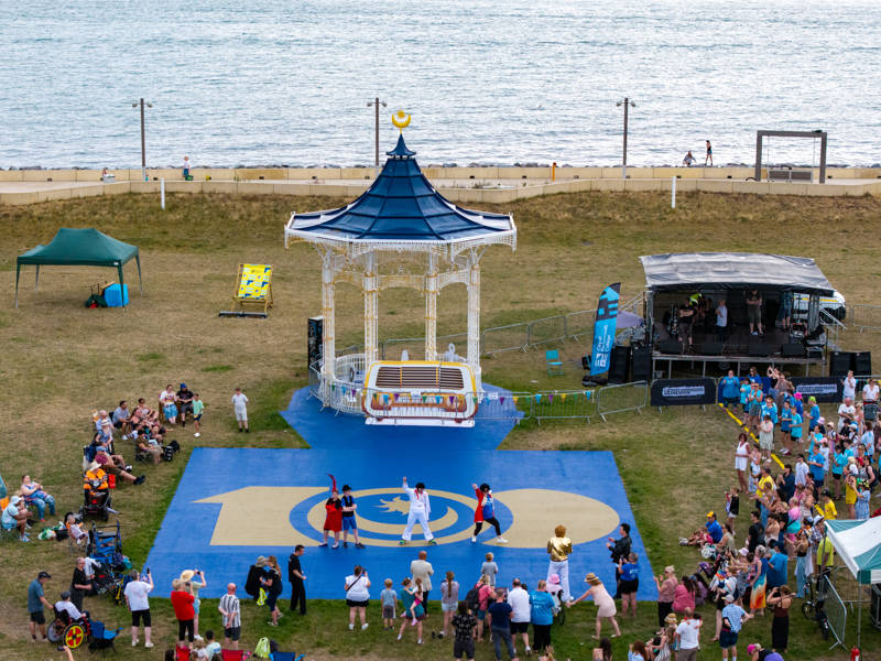 A group of people watch the City of Portsmouth College flashmob dance at Southsea Bandstand