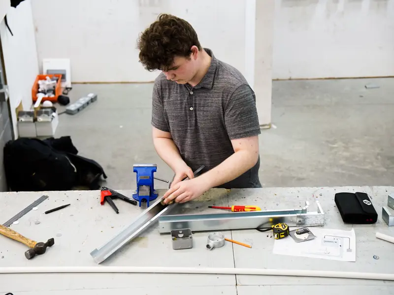 Young male student at a workbench as part of his Level 3 Electrical Installation/Maintenance (Electrician) Apprenticeship Standard.