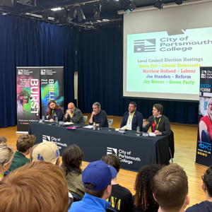The City of Portsmouth College hustings 2026, showing four candidates and politics lecturer Steve Fitzgerald, centre, at a table in front of an audience of students