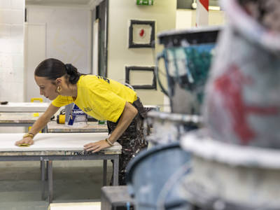 A female painting and decorating student sanding down a surface