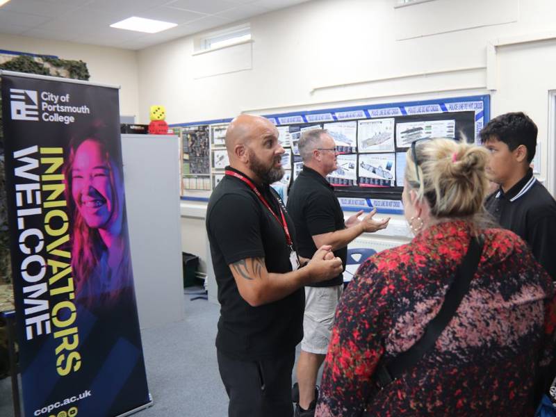 Lecturer talking to prospective students and parents at college Open Event.