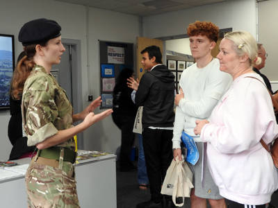 A UPS student in uniform talks to a young man and an older woman