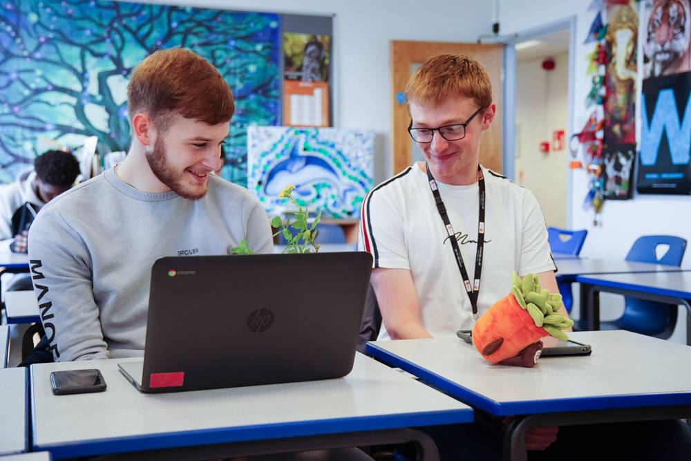 Students in classroom at desks with laptop and tablet.