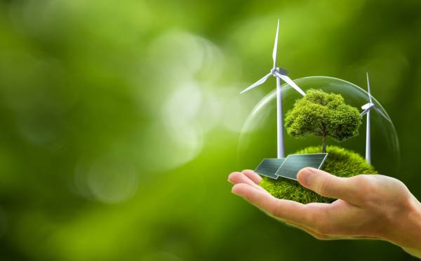 Hand holding a globe containing green energy.